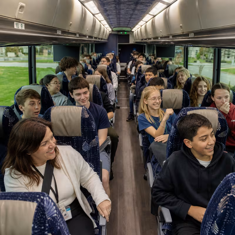 Group boarding a white charter bus for School Transportation transportation in New Orleans